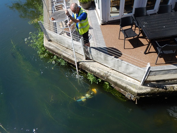 Diver in river with survey pole